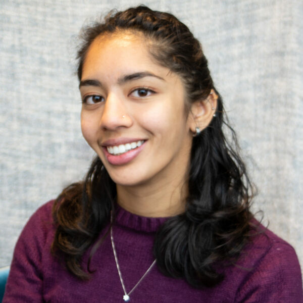 Photo of Ashna Mishra smiling at the camera, sporting a burgundy sweater.